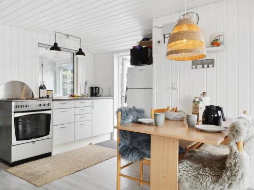 eine Küche mit einem Holztisch und eine Küche mit weißen Geräten in der Unterkunft Holiday Home Kielo - all inclusive - 200m to the inlet by Interhome in Løgstør