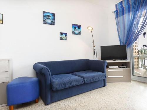 a living room with a blue couch and a tv at Apartment Riells Platja by Interhome in L'Escala