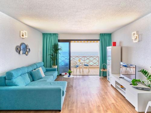 uma sala de estar com um sofá azul e vista para o oceano em Apartment Blue Neptuno-2 by Interhome em Puerto de Santiago