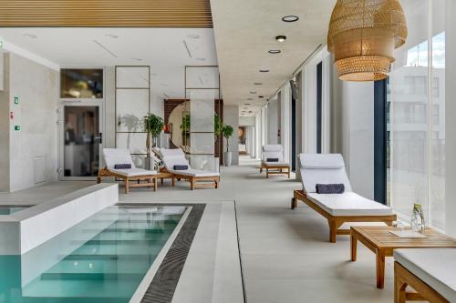 a hotel lobby with a swimming pool and chairs at GRANO APARTMENTS Solmarina SPA & Wellness in Wiślinka