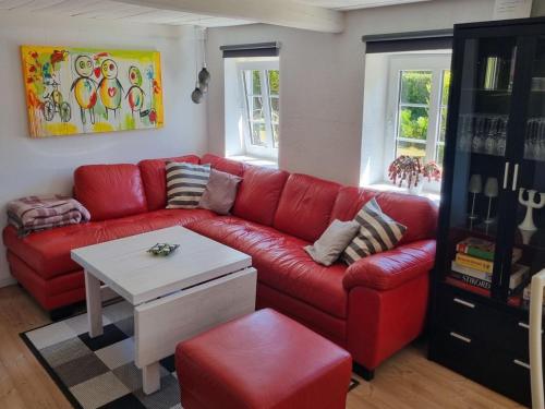 - un salon avec un canapé rouge et une table dans l'établissement Holiday Home Alisa - from the sea in NE Jutland by Interhome, à Hadsund