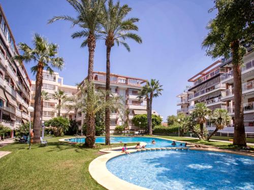 a swimming pool with palm trees and buildings at Apartment Dianium-1 by Interhome in Denia