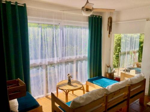 Un dormitorio con una ventana con cortinas verdes y una mesa en Casa Rural Una Ventana a la Montaña, en Aracena