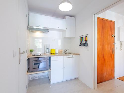 Elle comprend une petite cuisine avec des placards blancs et une porte en bois. dans l'établissement Apartment Le Victoria-9 by Interhome, à Saint-Aygulf