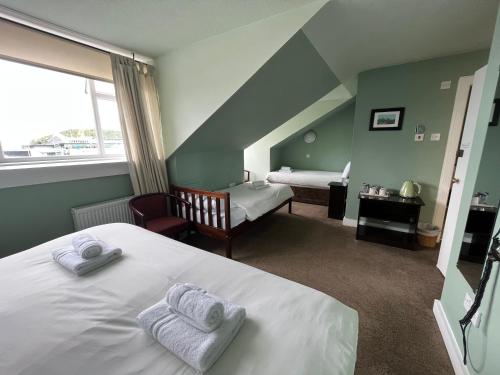 a bedroom with a white bed with towels on it at The Kelvin Hotel in Oban