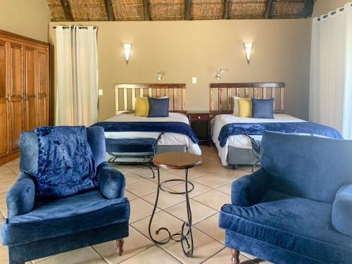 a hotel room with two beds and two chairs at Zebula Golf Estate and Spa - Zebula Golfers Lodge in Mabula