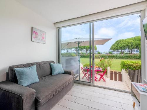 - un salon avec un canapé et une table avec un parasol dans l'établissement Apartment La Lagune-8 by Interhome, au Grau-du-Roi