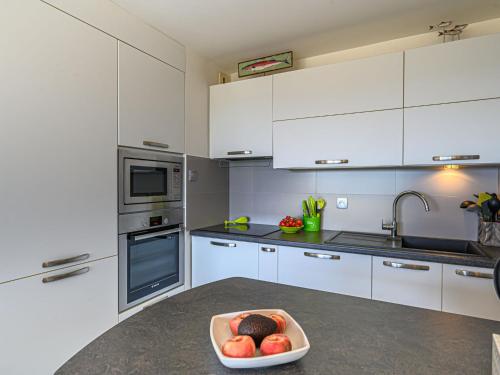 een keuken met witte kasten en een fruitschaal op een aanrecht bij Apartment Les Horizons-2 by Interhome in Carnac
