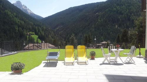 a patio with chairs and a table with a view of a mountain at Garni B&B Apartments Plank in Nova Levante