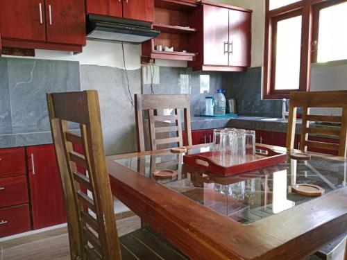 a kitchen with a glass table and wooden chairs at Home Stay Resort in Nilaveli