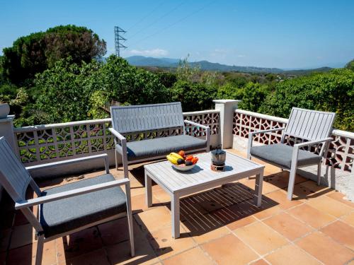 3 sillas y una mesa con un bol de fruta en el patio en Holiday Home Mas Altaba by Interhome, en Maçanet de la Selva