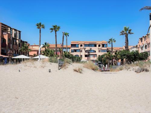 une plage de sable avec des palmiers et un bâtiment dans l'établissement Apartment Front de Mer-24 by Interhome, au Barcarès