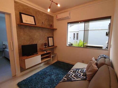 sala de estar con sofá, TV y ventana en Pier Sul Apartaments en Salvador