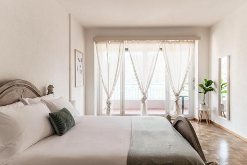 a bedroom with a white bed with a large window at Maraini 17 by Quokka 360 - panoramic flat near the station in Lugano