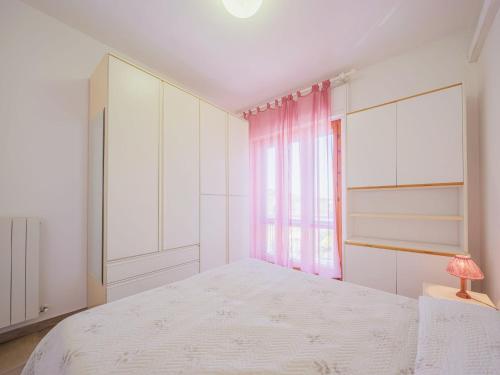a white bedroom with a bed and a window at Apartment Cinzia by Interhome in Viareggio