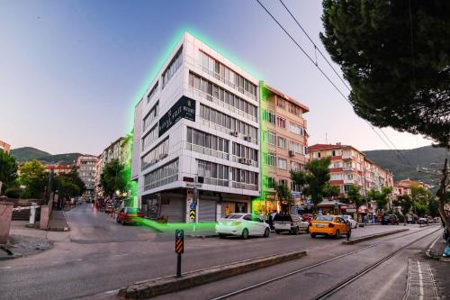 un grand bâtiment sur une rue de la ville avec des voitures garées dans l'établissement ROYAL SUİT, à Bursa