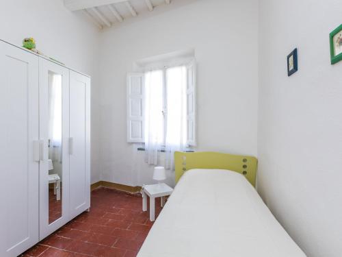a white bedroom with a bed and a window at Apartment Francesco's pretty house by Interhome in Riparbella