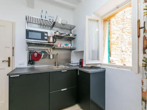 kuchnia z zielonymi szafkami i oknem w obiekcie Apartment Domus Mariae by Interhome w mieście Casale Marittimo