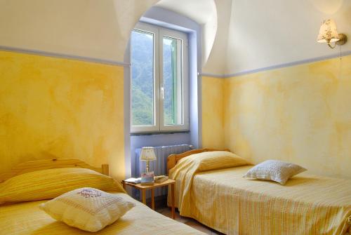 a bedroom with two beds and a window at La Casa dei Nonni Castelbianco in Castelbianco