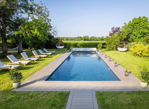une piscine dans une cour avec des chaises longues dans l'établissement Maison Belline, à Fontaine-Simon