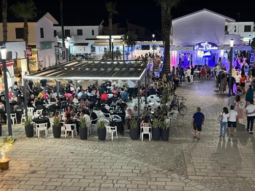 una folla di persone sedute ai tavoli in una strada di notte di B&B Villa Anna a Sibari