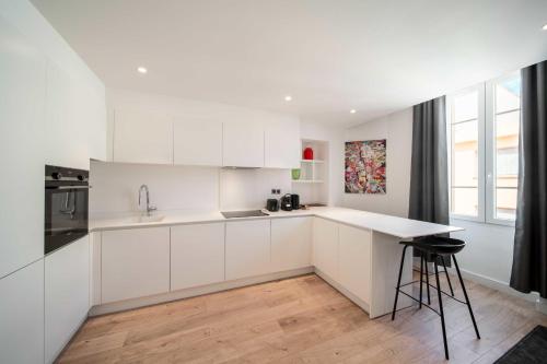 a white kitchen with white cabinets and a counter at Charming apartment for 4 people - Forville - 100m from the Old Port in Cannes