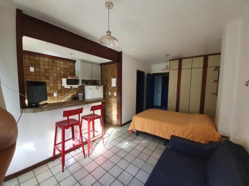 a bedroom with a bed and two red stools at Pier Sul Apart Service in Salvador