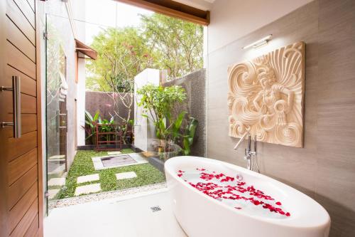 ein Bad mit einer weißen Badewanne und einem Fenster in der Unterkunft Villa DK - Bali in Nusa Dua