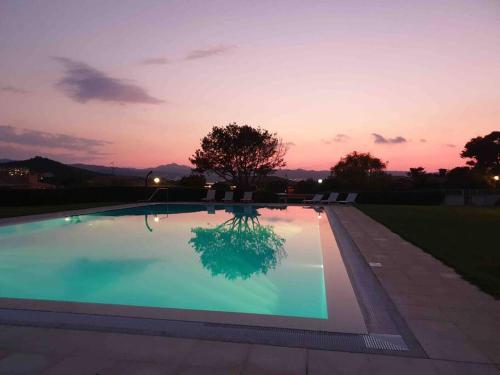 Cala BittaにあるVilla 200 mt from the beach - Baja Sardiniaの夕日を背景に広いスイミングプール