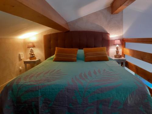 ein Schlafzimmer mit einem Bett mit einem Kopfteil aus Holz und zwei Lampen in der Unterkunft Gite Tropical 