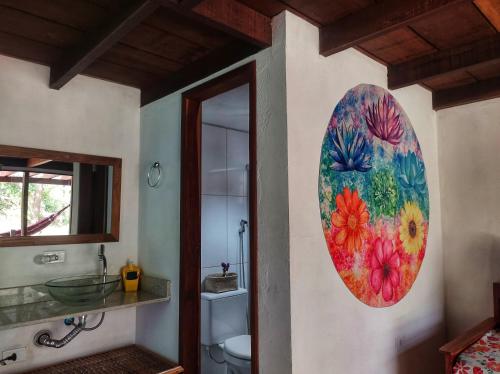 un baño con una pintura de flores en la pared en CHALÉS DA VILLA en Vale do Capao