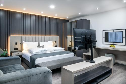 a bedroom with a bed and a tv and a couch at PARKHOTEL BRAUNAU - 24 Stunden Self Check-IN in Braunau am Inn