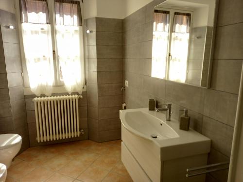 a bathroom with a sink and a toilet and a mirror at b&b isoladelsole in Perledo