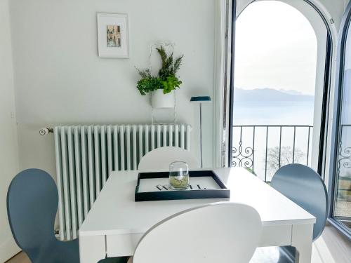 una mesa y sillas blancas con vistas a un balcón en Room with 360° view overlooking Lake Geneva and Alps, en Puidoux