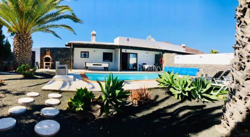 a house with a swimming pool and a palm tree at Villa Descansa with private pool, sea view, Sat-tv free Wifi in Playa Blanca