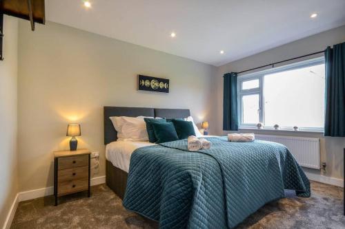 a bedroom with a bed with a blue blanket and a window at Potter's Escape-walking distance from The Studios! in Abbots Langley