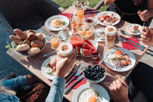 een groep mensen die rond een tafel zitten met eten bij dasKAISER - Dein Gartenhotel in Tirol in Ebbs