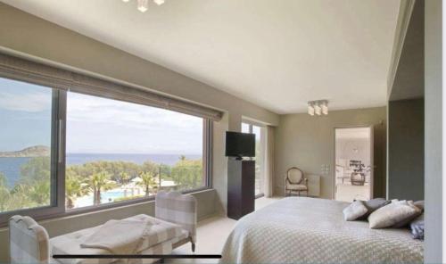 a bedroom with a bed and a large window at MEDOUSA VILLA in Porto Rafti