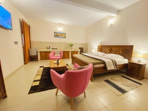 a bedroom with a bed and two pink chairs at Hôtel La Belle Etoile & SPA in Saly Portudal