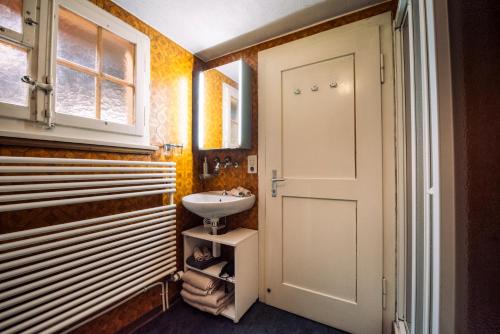 a bathroom with a sink and a white door at Ferienhaus Chalet Oberdorf in Brienz