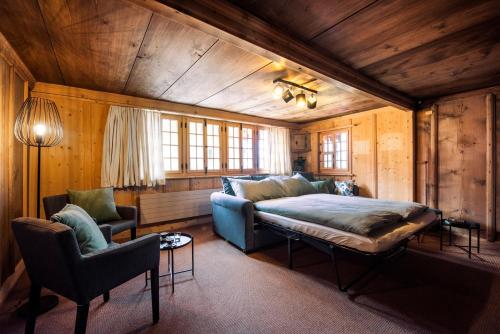 a bedroom with a bed and a couch and chairs at Ferienhaus Chalet Oberdorf in Brienz