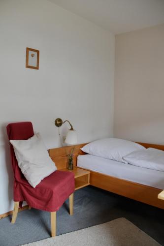 a bedroom with a bed and a red chair at Schildwirtschaft Zum Rothen Ochsen in Laupheim