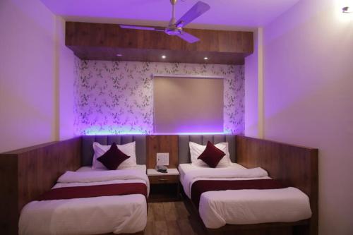 グワーハーティーにあるHOTEL DAISYの紫色の照明が備わる客室内のベッド2台