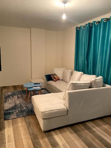 a living room with a white couch and blue curtains at Meelmak apartment in Nairobi