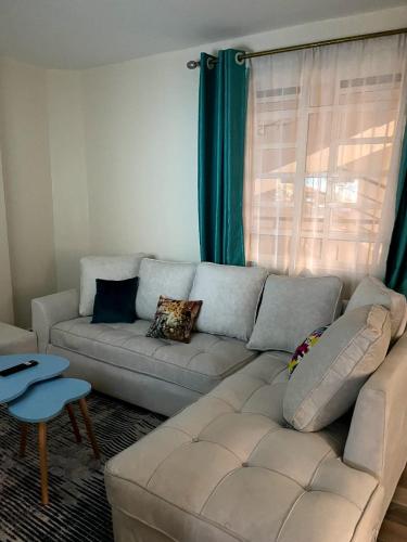 a living room with a white couch in front of a window at Meelmak apartment in Nairobi