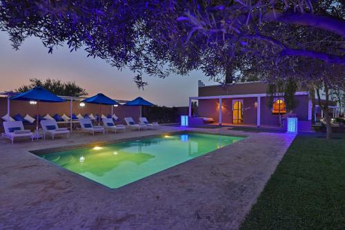 a swimming pool in the backyard of a house at night at DOMAINE DU DOUAR in Marrakech