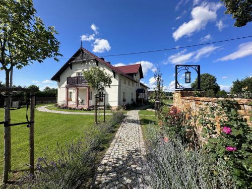 a white house with a garden and a pathway at Dworek Wojanów in Wojanów