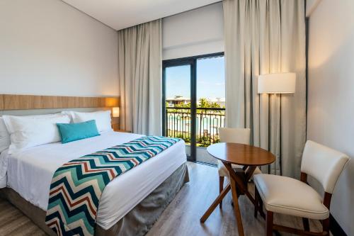 a bedroom with a bed and a table and a window at Japy Golf Resort Hotel in Cabreúva
