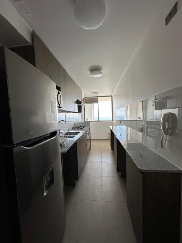 Il comprend une grande cuisine équipée d'un réfrigérateur et d'un évier. dans l'établissement Departamento 3D2B Condominio Altos de Huayquique, à Iquique