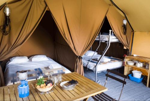 Zimmer mit einem Zelt mit einem Tisch und einem Bett in der Unterkunft Huttopia De Meinweg in Herkenbosch